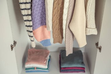 Yünlü bej örgü süveterler üst üste dizilip dolaba asılmış.