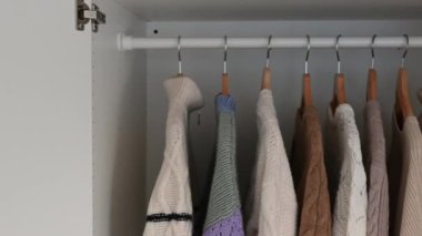 Asılı dolaptaki kıyafetlerin yakın çekim videosu. Kamera yatay olarak hareket ediyor