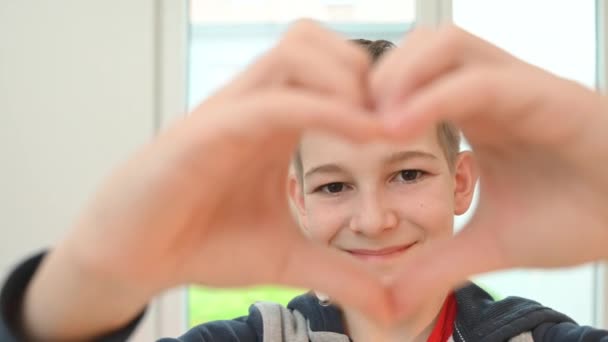 Χαμογελώντας Έφηβος Αγόρι Δείχνει Σχήμα Καρδιάς Δάχτυλά Του — Αρχείο Βίντεο