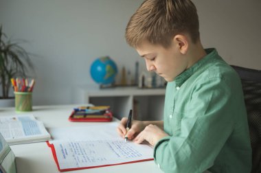Çalışkan tenn öğrenci çevrimiçi kurs sırasında masada oturuyor ve evde çalışıyor.