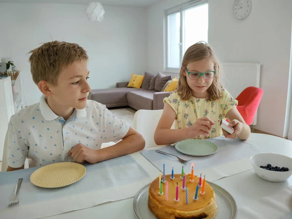 自宅でテーブルでトートとカラフルなキャンドルを持つ誕生日パーティーで幸せな子供たちの肖像画 — ストック写真