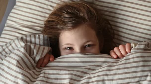可爱的小女孩躲在舒适的床上 眼睛望着外面 — 图库视频影像