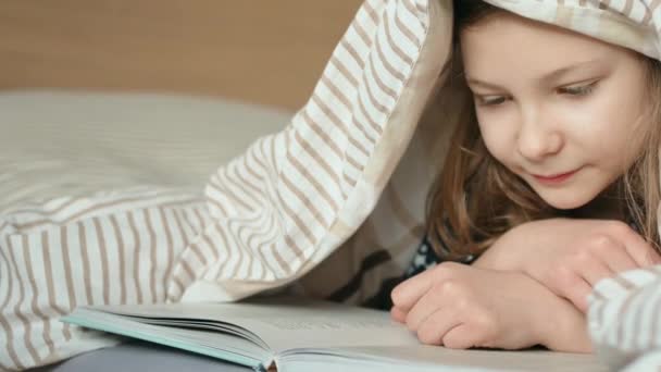 Симпатична Маленька Дівчинка Підліток Лежить Читає Книгу Ліжку Під Ковдрою — стокове відео