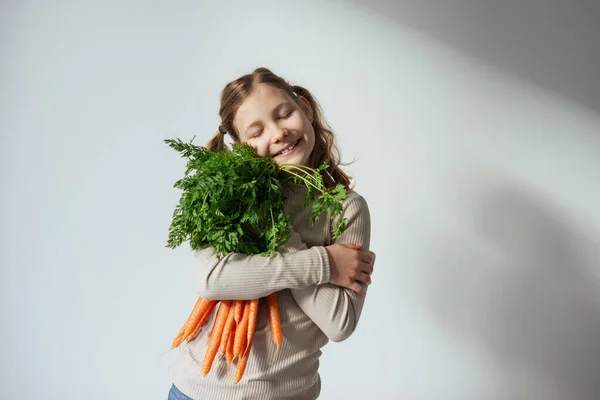 微笑的少女 手里拿着一束绿叶新鲜的橙子胡萝卜 — 图库照片