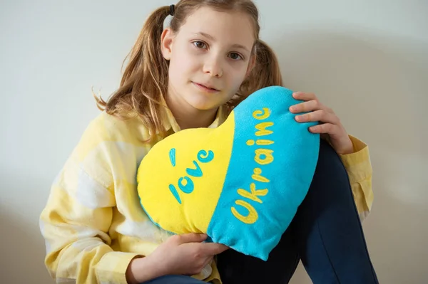 可爱的少女坐在地板上 拿着一个乌克兰国旗色的枕头 — 图库照片