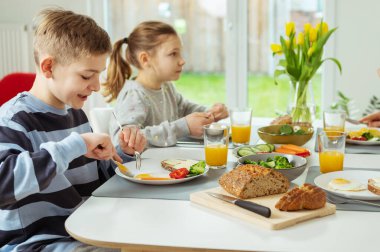 Genç erkek ve kız kardeş okuldan önce evde sağlıklı kahvaltı yapıyorlar.