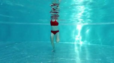 4K 60fps kırmızı mayo giymiş koşan küçük bir kızın su altında videosu.