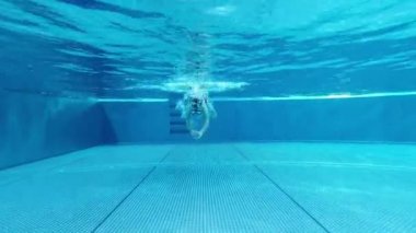 Güneşli bir günde mavi yüzme havuzunda mayo giymiş küçük bir kızın 4K videosu.