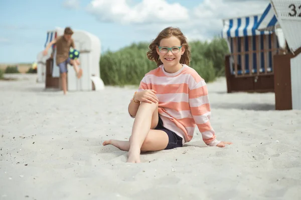 Счастливая Девочка Подросток Сидящая Белом Пляже Брат Заднем Плане Играют — стоковое фото