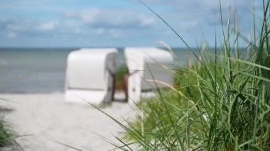 Beyaz kumlu, kumlu, kumullu, çimenli, plaj sandalyeli ya da Kuzey Almanya 'daki strandkorb' un 4K yavaş çekim videosu.