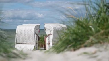 Beyaz kumlu, kumlu, kumullu, çimenli, plaj sandalyeli ya da Kuzey Almanya 'daki strandkorb' un 4K yavaş çekim videosu.