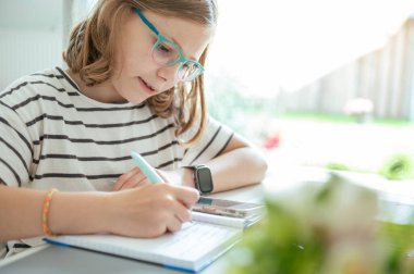 Blonde teen schoolgirl doing her homework after classes