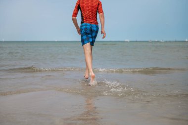 Sporty young boy running in sea at beautiful beach at summer vocation
