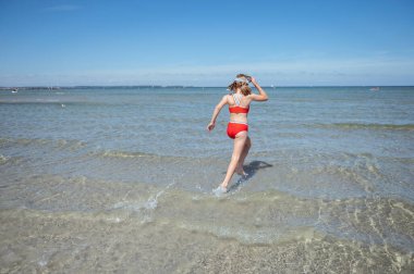 Happy child girl running and enjoying summer in water at sea at vocation