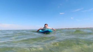 Handsome teen boy lying swim on sup board in sea at summer vacationsummer vocation