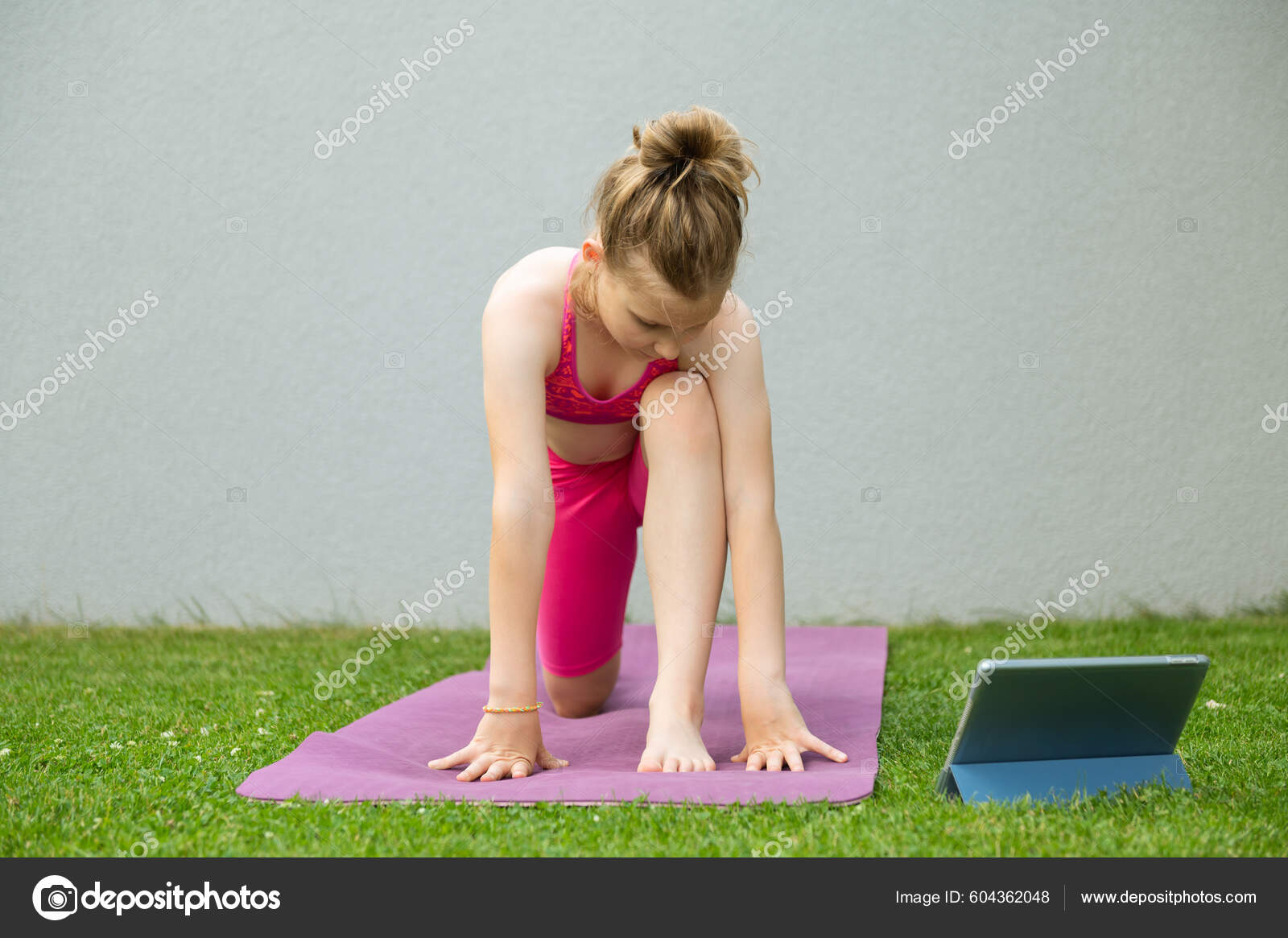 Happy beautiful child girl doing stretching exercises on yoga mat