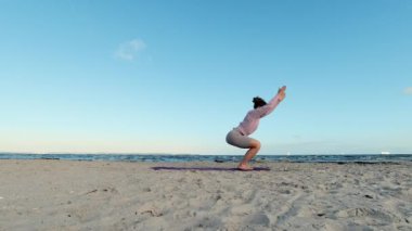 4k slow motion video of a girl doing morning yoga routine  at the beach of Baltic sea