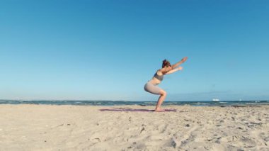 4k slow motion video of a girl doing morning yoga routine  at the beach of Baltic sea