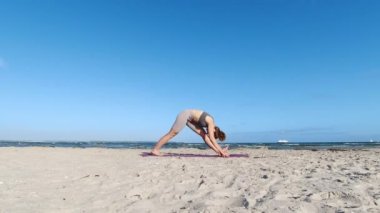 4k 60fps morning yoga routine at Baltic sea coastline over clear blue sky with large vessel in background