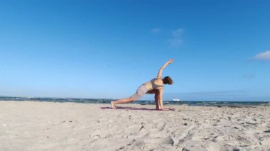 4k 60fps morning yoga routine at Baltic sea coastline over clear blue sky with large vessel in background