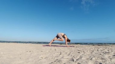 4k 60fps morning yoga routine at Baltic sea coastline over clear blue sky with large vessel in background
