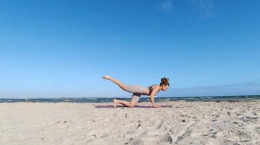 4k 60fps morning yoga routine at Baltic sea coastline over clear blue sky with large vessel in background