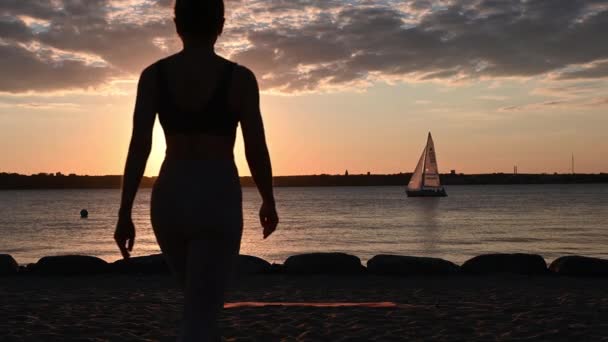 日落时一位妇女在波罗的海沿岸做瑜伽运动的慢镜头 — 图库视频影像