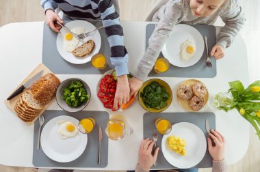 Aile sağlıklı bir kahvaltı yapıyor. Düz görünüm üstten