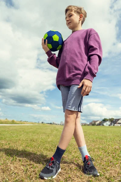 ハンサムなティーン子供男の子と一緒にボールで緑のフィールドで夏休み — ストック写真