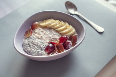 Sağlıklı kahvaltı: mısır gevreği, üzüm, muz ve gümüş kaşıklı chia.