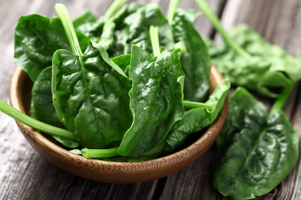 Spinach leaves in a wooden plate — Stock Photo, Image