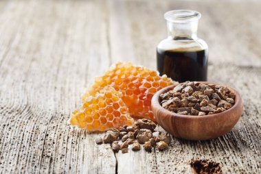 Propolis tincture with honeycombs on wooden board clipart