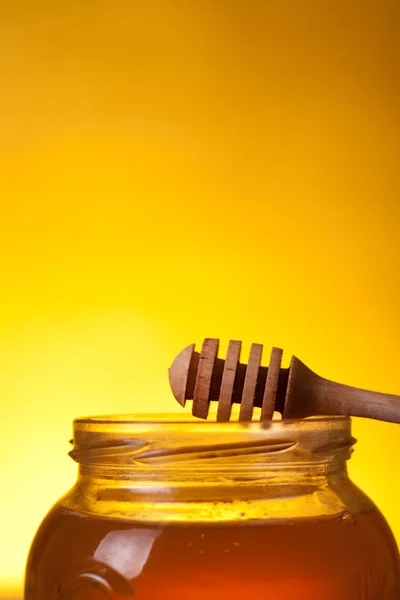 Close-up shot of honey jar with dipper — Stock Photo, Image