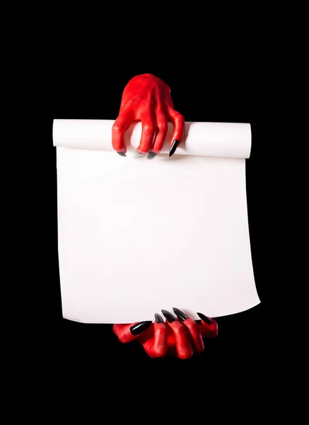 Red devil hands with black nails holding blank paper scroll — Stock Photo, Image