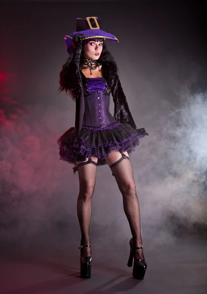 Söt häxa i lila och svarta gothic halloween-kostym — Stockfoto