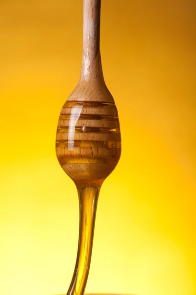 Close-up shot of a wooden dipper with flowing honey — Stock Photo, Image