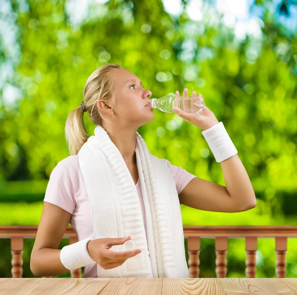 Una ragazza che beve acqua da una piccola bottiglia — Foto Stock