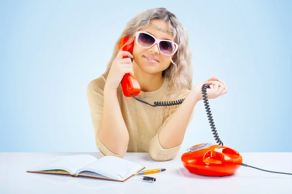A young blonde at table with telephone — Stock Photo, Image