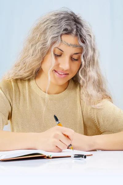 A blonde writing in notepad — Stock Photo, Image