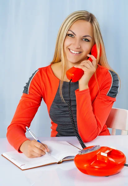 A smiling blonde in red dress with phone — Stock Photo, Image