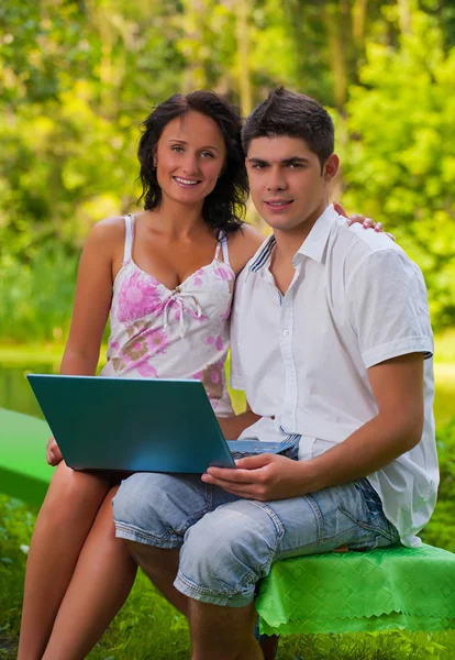 Paar sitzt mit Laptop im Park — Stockfoto