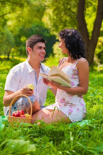 Pár s knihou a apple v parku — Stock fotografie