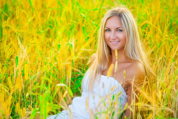 Een beautyful blond zitten in de tarwe — Stockfoto