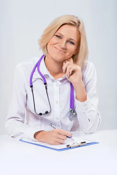 Amigável médico feminino sentado à mesa — Fotografia de Stock