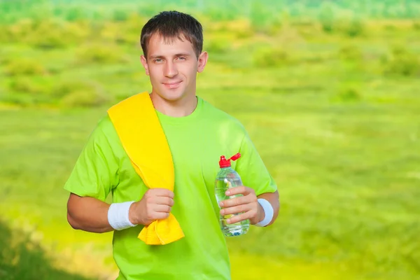 A sports man with towel holding bottle of water — Stock Photo, Image