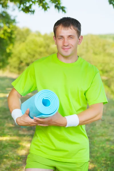 Un uomo in possesso di tappetino yoga — Foto Stock