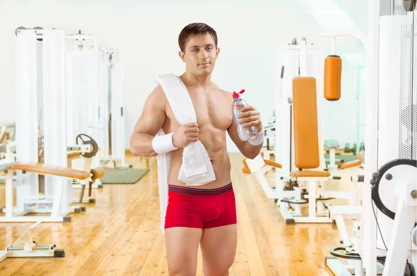 Sportovec v gim drží láhev vody — Stock fotografie