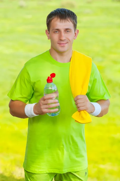 Un sportif tenant une bouteille d'eau et regardant la caméra — Photo