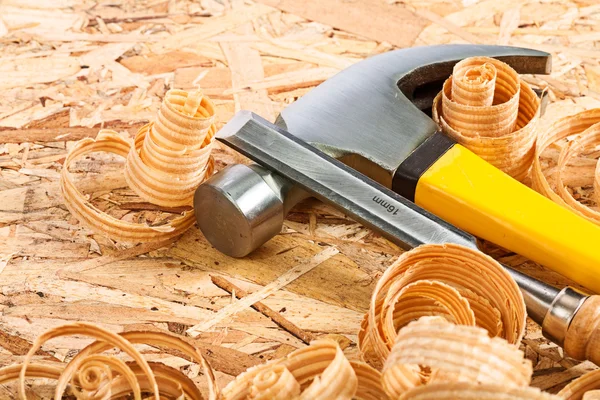 Claw hammer and carpenter chisel with wooden chips — Stock Photo, Image