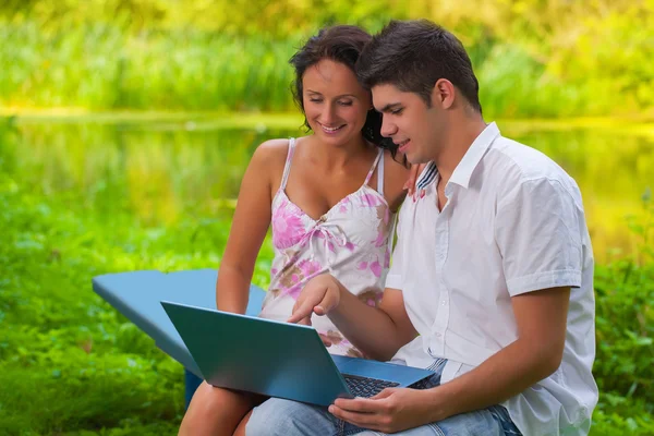 Glückliches Paar sitzt mit Laptop — Stockfoto